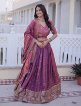 Woman in a traditional purple and gold saree standing on a balcony.