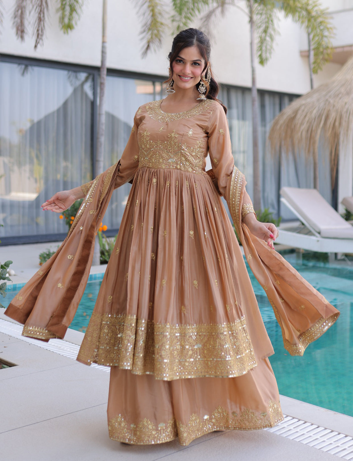 Woman in a peach and gold traditional outfit by a pool