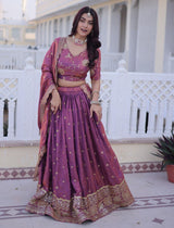 Woman in a traditional pink and gold outfit standing on a balcony.