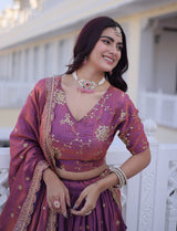 Woman in a traditional purple outfit with gold embroidery, smiling outdoors.