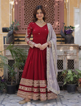 Woman in a red traditional outfit with gold details standing in an indoor setting.