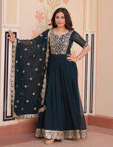 Woman wearing a dark blue traditional outfit with a matching dupatta in a decorated room.
