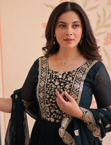 Woman wearing a black and gold embroidered traditional outfit against a floral background