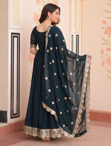Woman wearing a dark blue traditional outfit with a matching dupatta in an indoor setting.