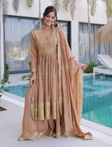 Woman in a beige and gold traditional outfit by a poolside.