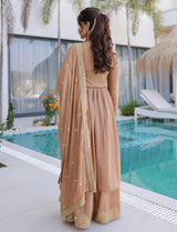 Woman in a beige saree standing by a poolside