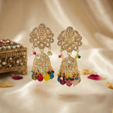 Ornate gold earrings with colorful beads on a soft beige background
