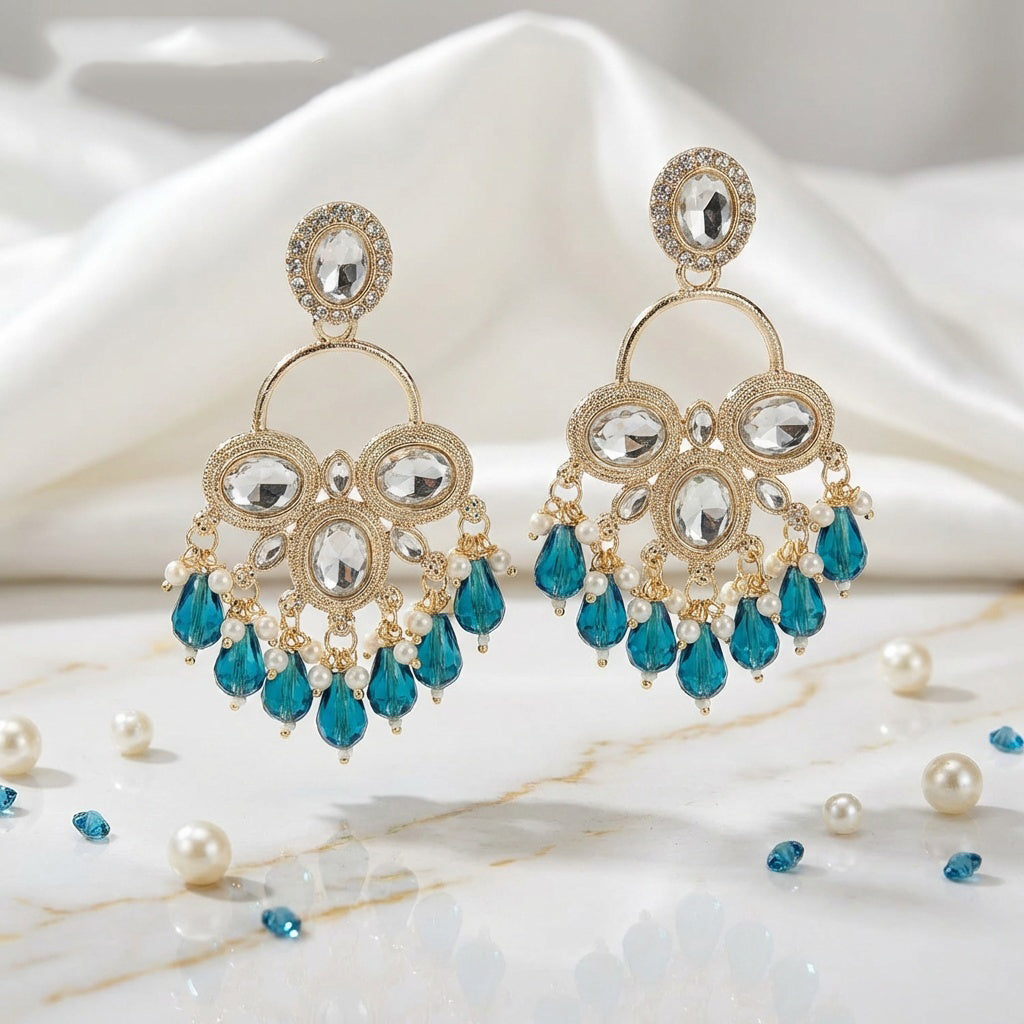 Gold and blue earrings on a marble surface with pearls.