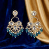 Pair of ornate earrings with blue gemstones on a blue and gold fabric background