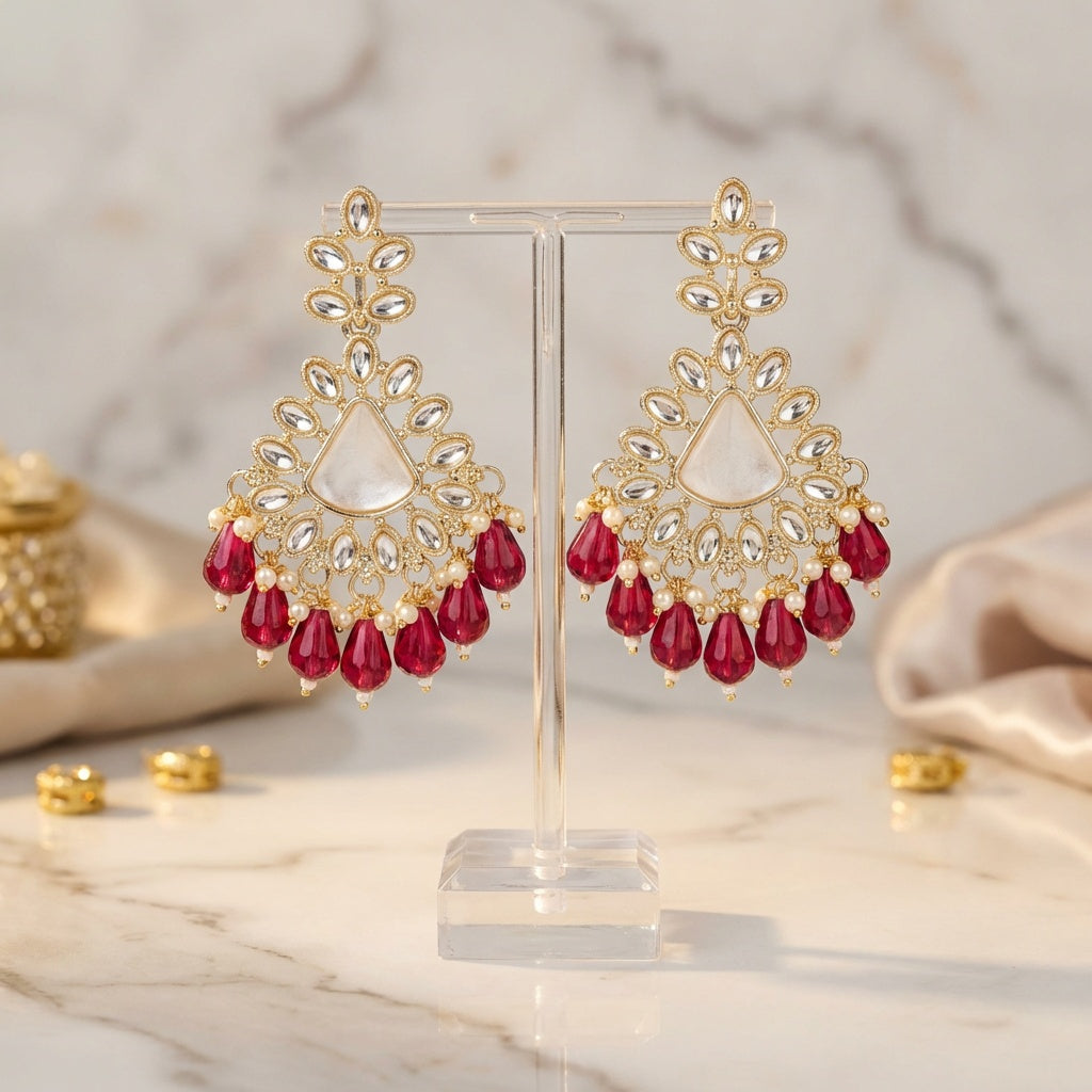 Gold and red earrings on a stand with a marble background