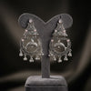 Pair of silver earrings with dolphin design on a gray stand against a dark background