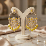 Decorative earrings with yellow stones on a beige stand against a neutral background