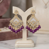 Gold and purple earrings on a white stand with a blurred background
