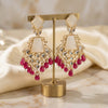 Gold and red earrings on a gold stand with a soft beige background