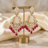 Gold and red earrings on a gold stand with a soft beige background