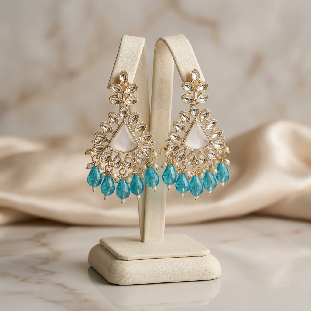 Gold and turquoise earrings on a display stand with a soft background