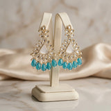 Gold and turquoise earrings on a display stand with a soft background