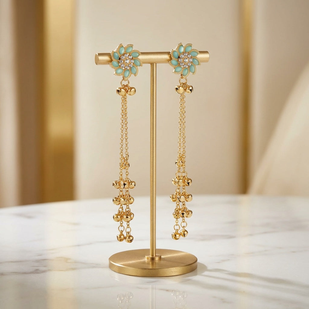 Gold earrings with turquoise stones on a gold stand against a beige background