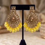 Gold and yellow earrings on a black stand with a blurred background