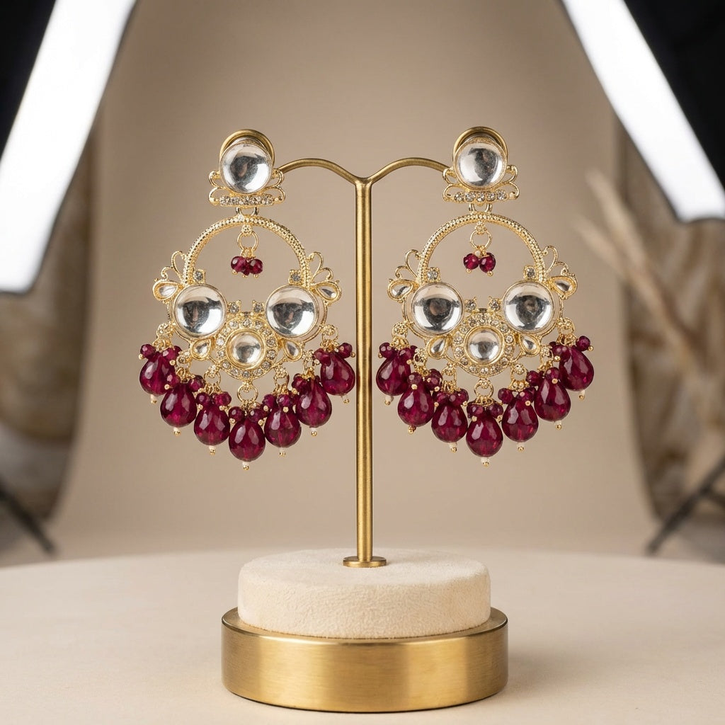 Ornate earrings with red beads on a gold stand against a neutral background