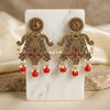 Ornate earrings with red and pearl details on a marble stand.
