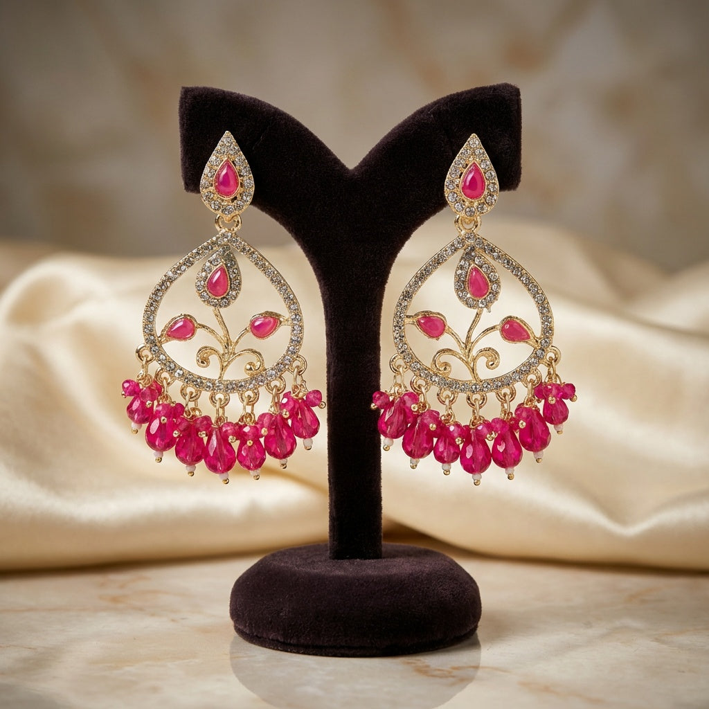 Pair of pink and gold earrings on a black stand with a beige fabric background