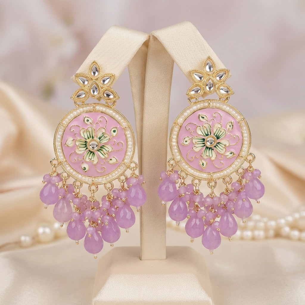 Ornate earrings with pink stones and gold accents on a stand.