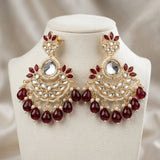 Ornate earrings with red gemstones on a mannequin bust.