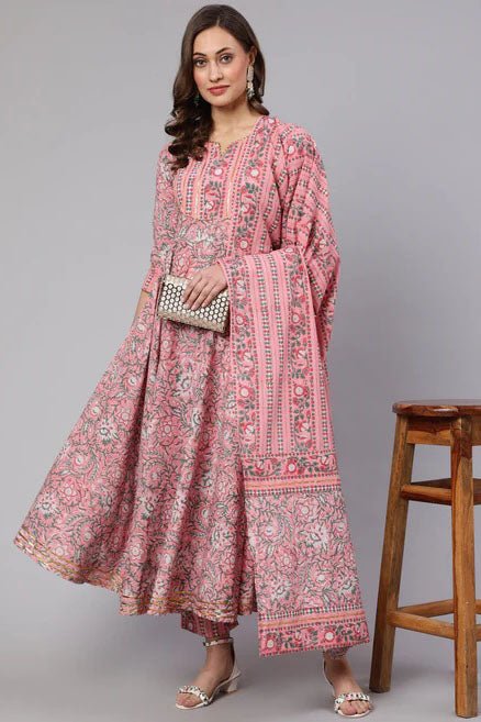 Woman wearing a pink patterned dress with a wooden stool in the background