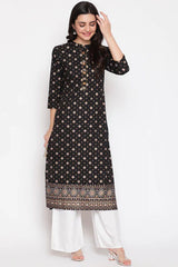 Woman wearing a black patterned kurta with white pants on a white background